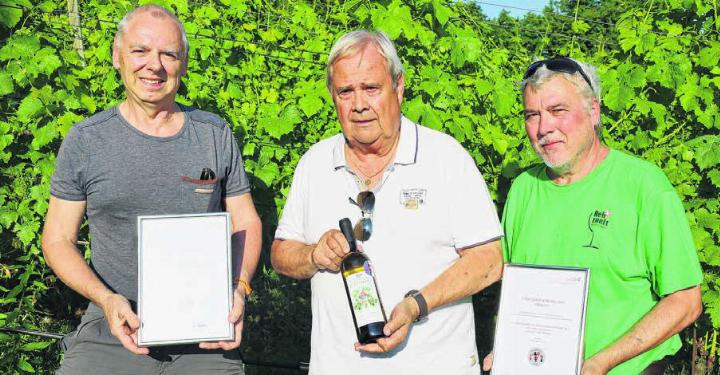Stolze Vertreter der Rebzunft Bottmingen: Arthur Doppler, Franz Wunderer und Stephan Hirschi (von links) posieren mit dem Staatswein 2025 und den entsprechenden Urkunden. Foto: Alan Heckel